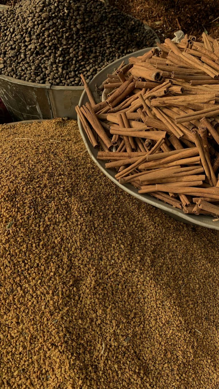 Close-up of cinnamon sticks and seeds at an outdoor spice market.