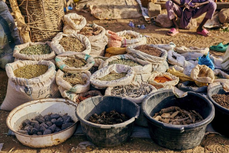 Colorful display of spices and herbs in an outdoor market setting, perfect for culinary enthusiasts.
