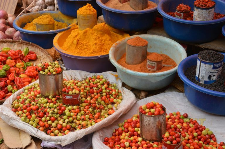 Colorful spices and fresh produce beautifully arranged at an outdoor market.